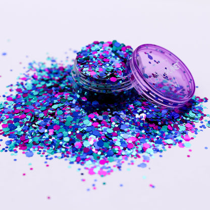 Multicolored glitter spilling out of a purple container on a light background