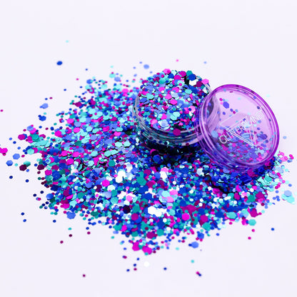 Colorful glitter scattered around an open purple container on a white background